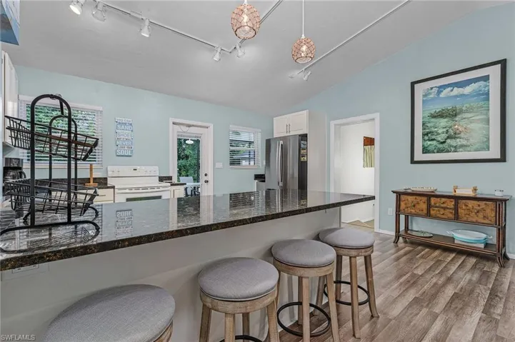 Kitchen featuring electric stove, white cabinetry, wood finished floors, healthy amount of natural light, and lofted ceiling
