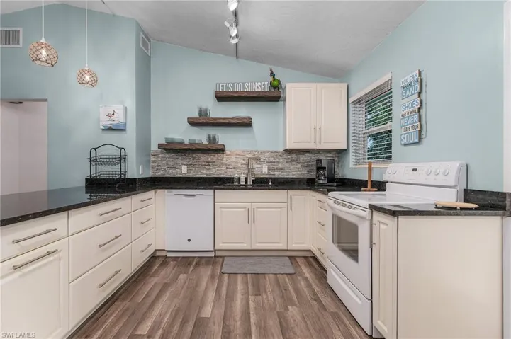 Kitchen with lofted ceiling, white appliances, open shelves, dark wood-style flooring, and backsplash