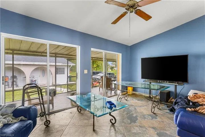 Living room featuring tile patterned flooring, ceiling fan, and vaulted ceiling