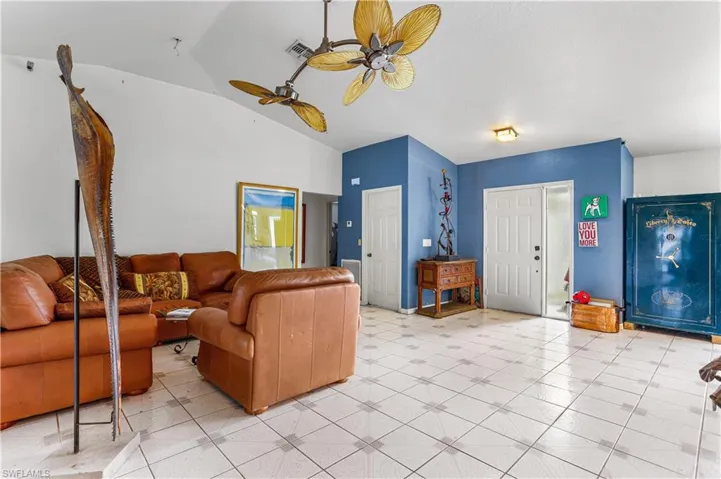 Tiled living room with ceiling fan and vaulted ceiling