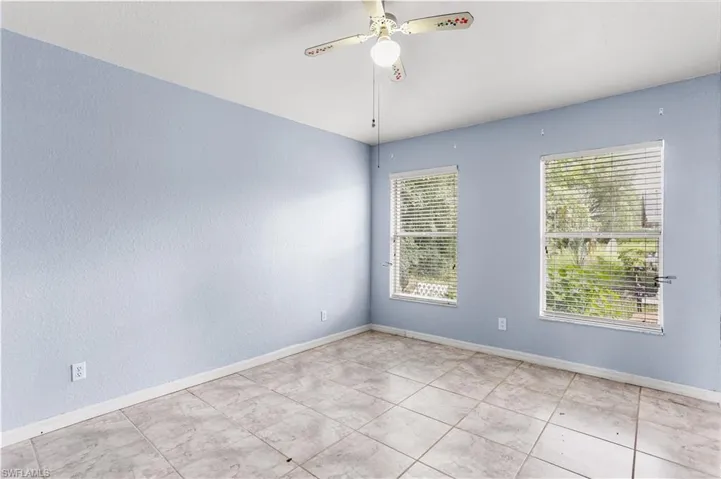 Tiled spare room featuring ceiling fan