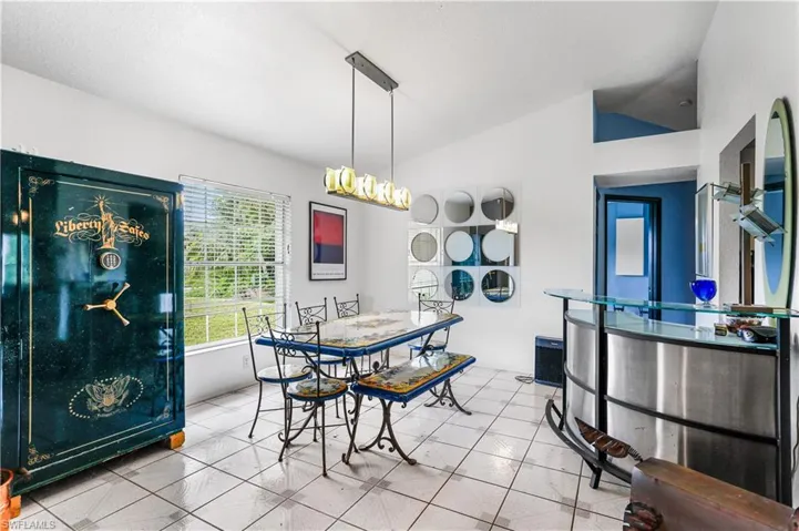 Tiled dining room featuring lofted ceiling