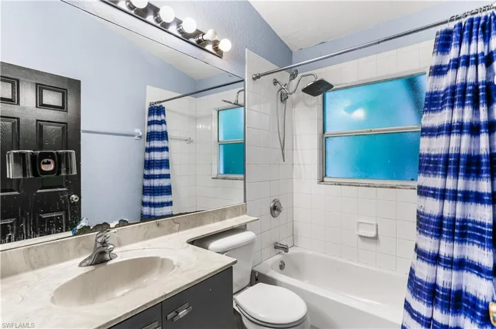 Guest bathroom with shower / bath combination with curtain, toilet, and vanity