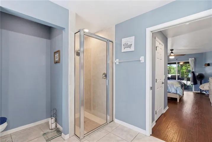 Ensuite bathroom with a stall shower, light tile patterned floors, and a ceiling fan