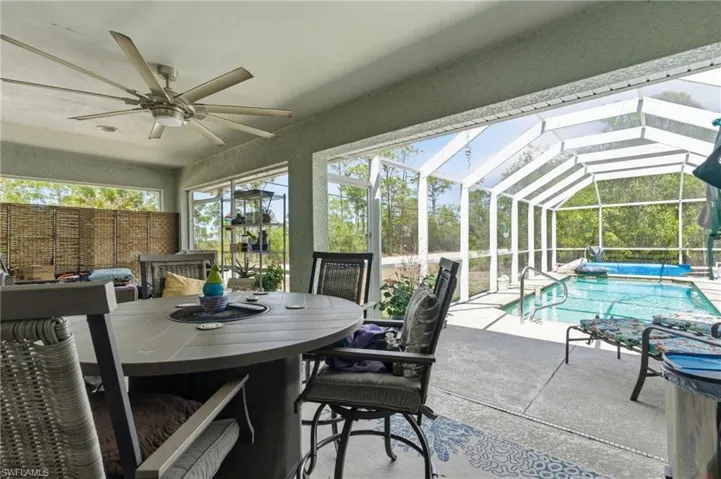 Sunroom featuring a patio, outdoor dining space, a ceiling fan, and a swimming pool