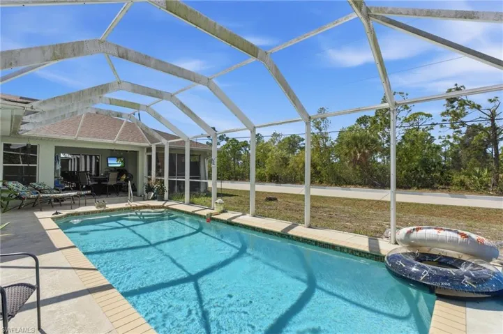 Swimming pool with glass enclosure, a sunroom, a lawn, and a patio