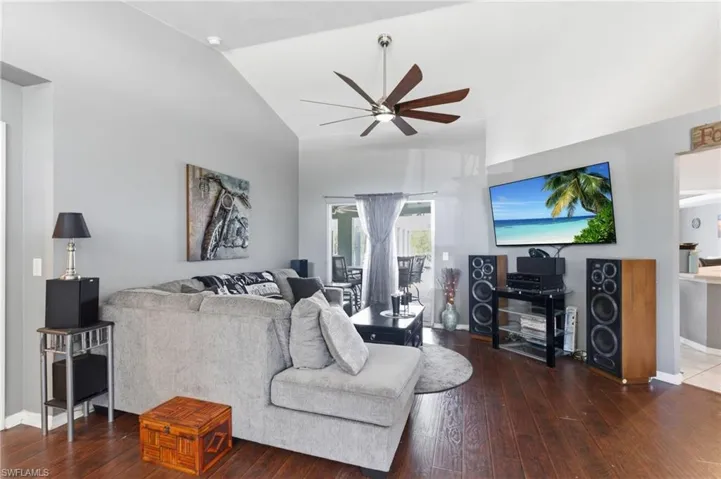 Living room featuring ceiling fan, dark wood-style floors, and lofted ceiling