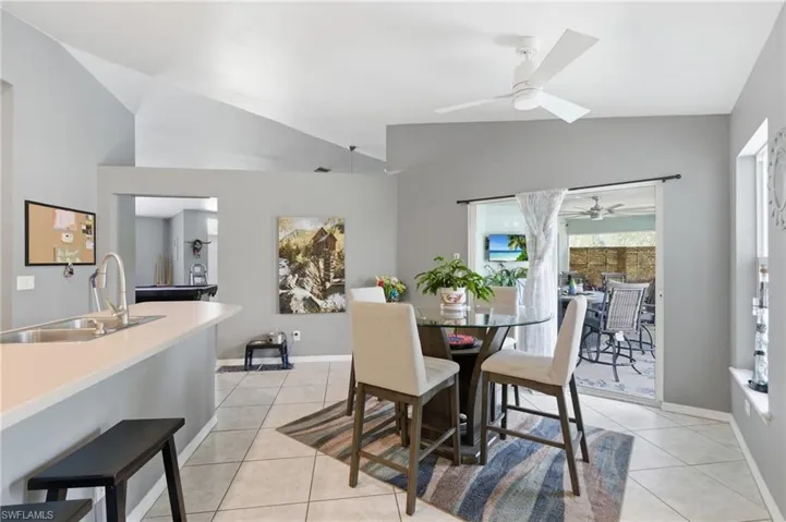 Dining space featuring vaulted ceiling, light tile patterned flooring, and ceiling fan