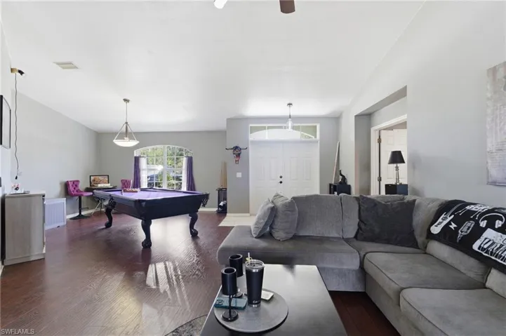 Living room with billiards table, dark wood-type flooring, lofted ceiling, and ceiling fan