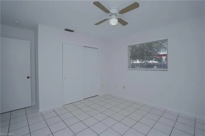 Room featuring white tile flooring, a ceiling fan with light fixture, and a window with blinds