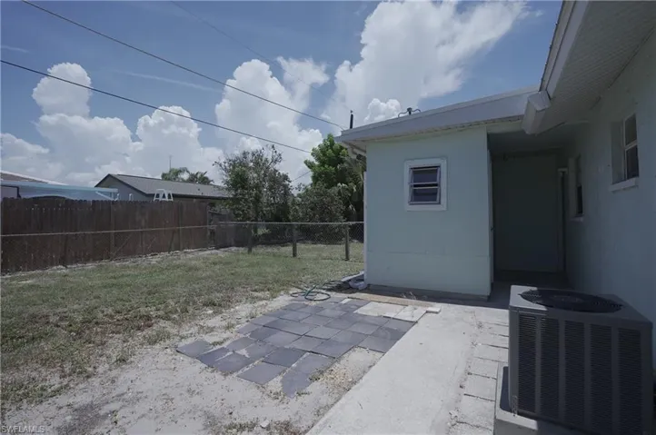 The property features a fenced yard, a patio area with pavers, and an external air conditioning unit