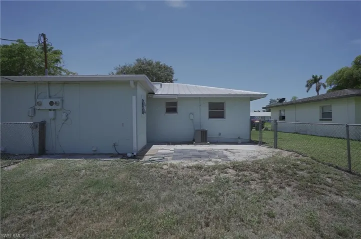 The property features a patio area with pavers, a chain-link fence, and a metal roof