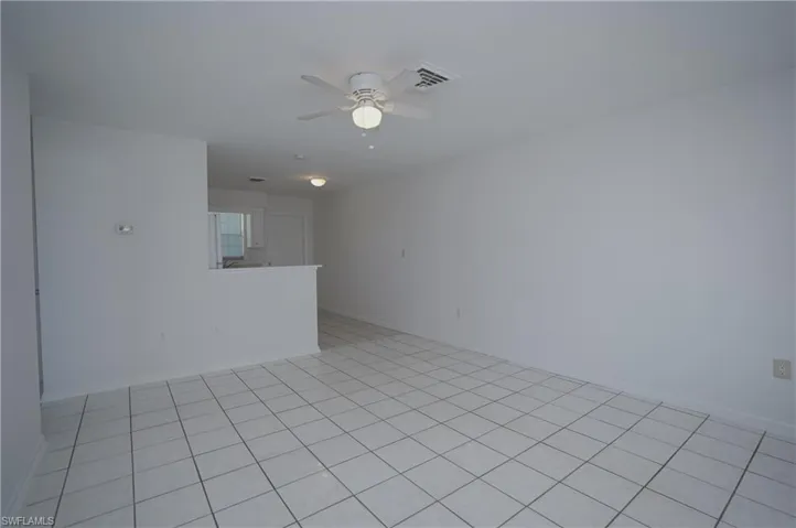 Living area featuring white tile flooring, light-colored walls, and a ceiling fan