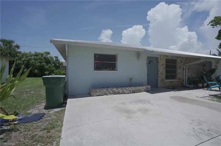 The property features a light blue exterior with stone accents, a concrete driveway, and a white roof