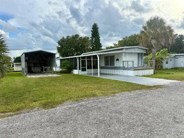 View of front of property with driveway, a front yard, a carport, and a sunroom