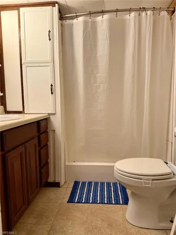Full bath featuring vanity, a shower with shower curtain, and tile patterned floors