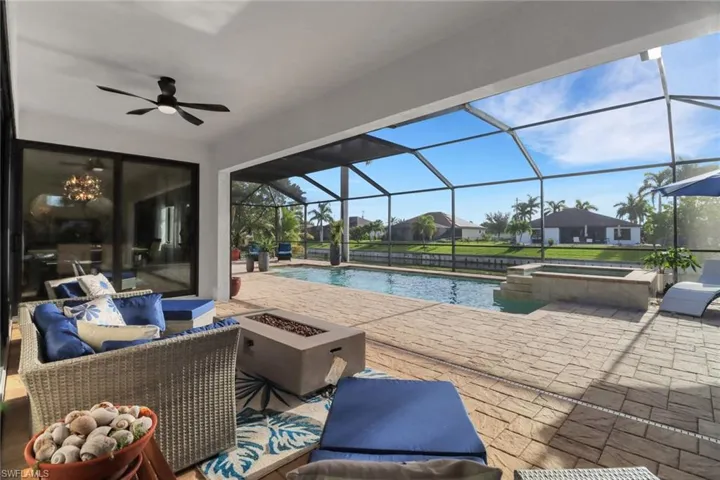 View of swimming pool with a patio, a sunroom, a pool with connected hot tub, an outdoor living space with a fire pit, and a lanai