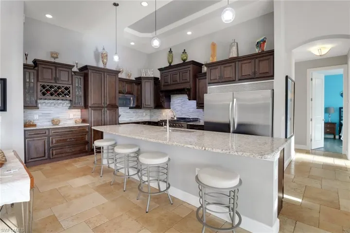 Kitchen featuring a kitchen breakfast bar, dark brown cabinets, appliances with stainless steel finishes, tasteful backsplash, and recessed lighting