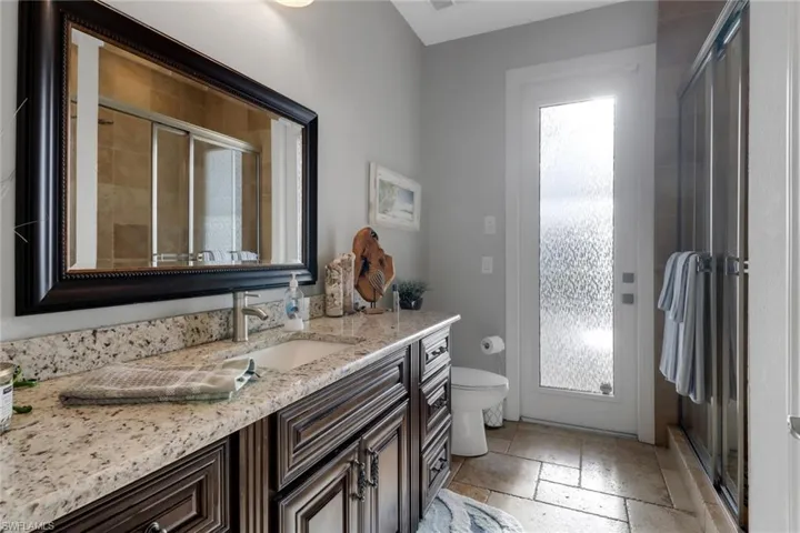 Full bathroom with vanity, a stall shower, and stone tile flooring