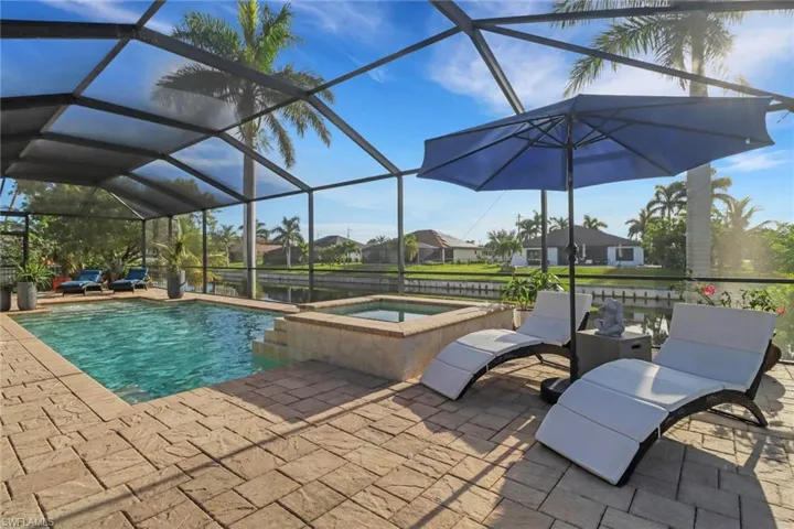 View of pool featuring a lanai, a patio area, a pool with connected hot tub, and a sunroom