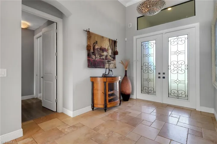 Entrance foyer with french doors, stone tile flooring, and ornamental molding