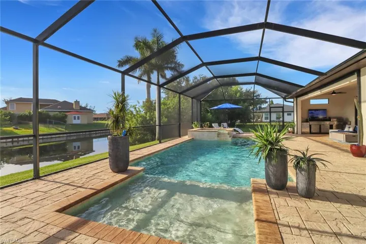 View of pool featuring an outdoor kitchen, a sunroom, a patio area, a pool with connected hot tub, and a lanai