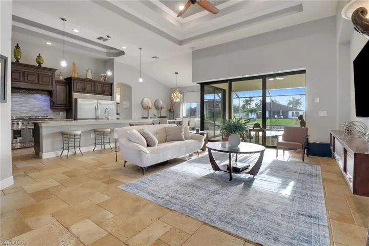 Living area featuring a high ceiling, a chandelier, a raised ceiling, recessed lighting, and a ceiling fan