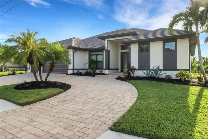 View of front of property with decorative driveway, a front lawn, stucco siding, an attached garage, and a tile roof