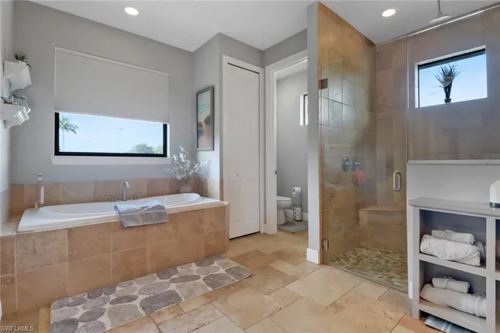 Full bath with a garden tub, a stall shower, stone tile flooring, recessed lighting, and a closet