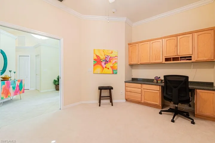 Carpeted office featuring built in desk and ornamental molding
