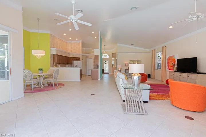 Living room with ornamental molding, high vaulted ceiling, a wealth of natural light, and ceiling fan