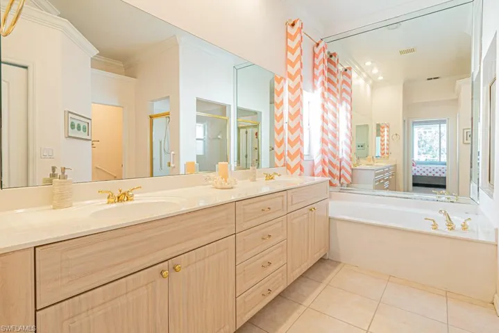 Bathroom with tile patterned flooring, vanity, crown molding, and independent shower and bath