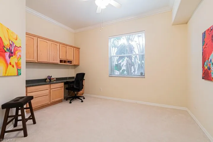 Office featuring ornamental molding, built in desk, light colored carpet, and ceiling fan