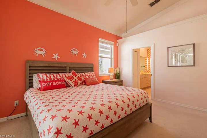 Carpeted bedroom featuring crown molding, ceiling fan, connected bathroom, and vaulted ceiling