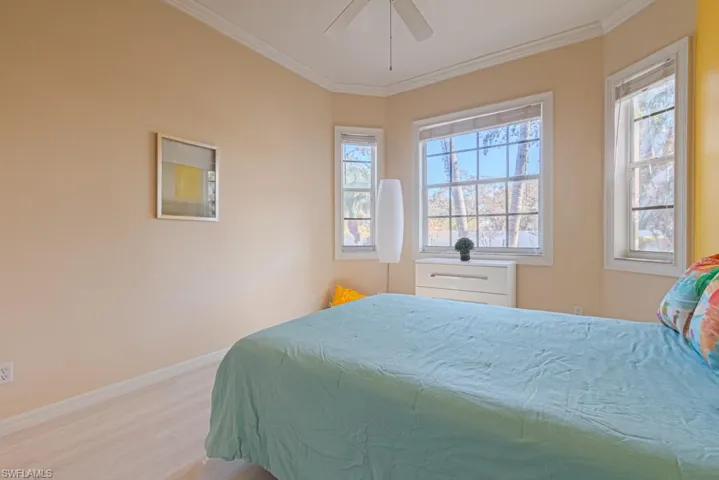 Bedroom with multiple windows, crown molding, and light hardwood / wood-style floors