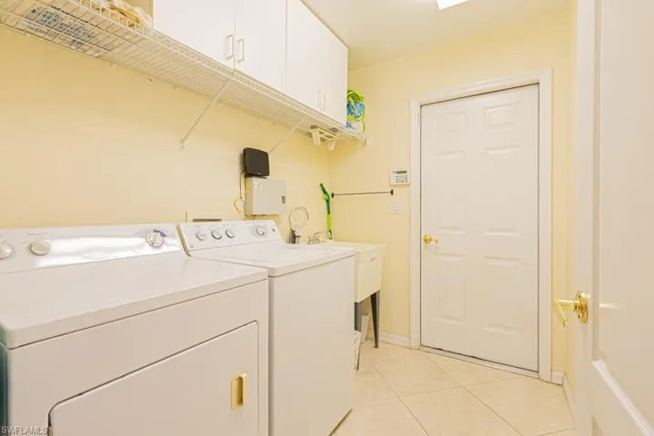 Clothes washing area with cabinets, light tile patterned flooring, and independent washer and dryer