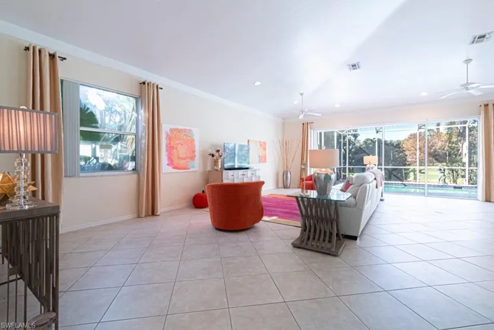 Tiled living room with plenty of natural light, ornamental molding, and ceiling fan