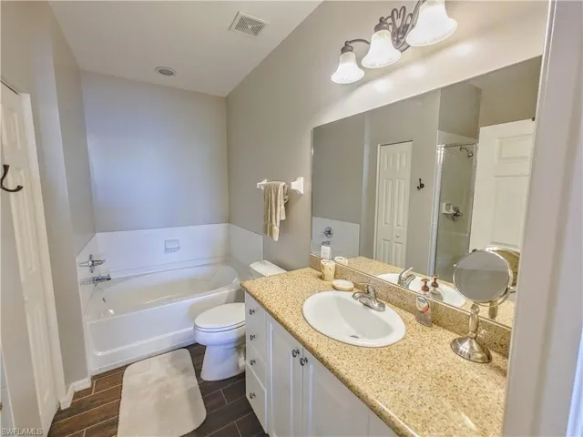 Bathroom with tile floors, oversized vanity, toilet, and a bath