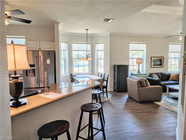 Kitchen featuring a breakfast bar area, stainless steel fridge, ceiling fan, and dark hardwood / wood-style floors
