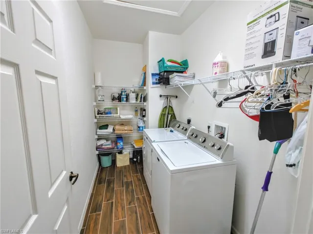 Laundry area with dark wood-type flooring, hookup for a washing machine, washer and clothes dryer, and electric dryer hookup