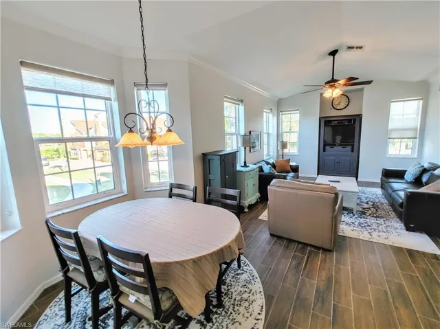 Dining room featuring dark wood-type flooring, plenty of natural light, ceiling fan, and lofted ceiling