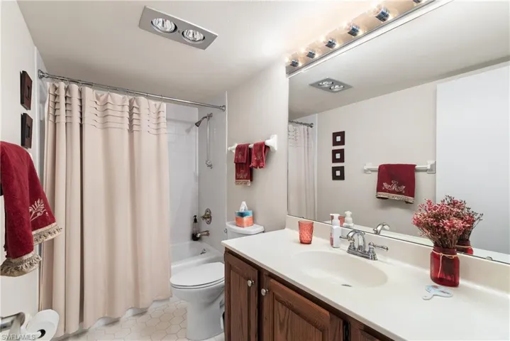 Bathroom featuring vanity, shower / tub combo with curtain, and light tile patterned flooring