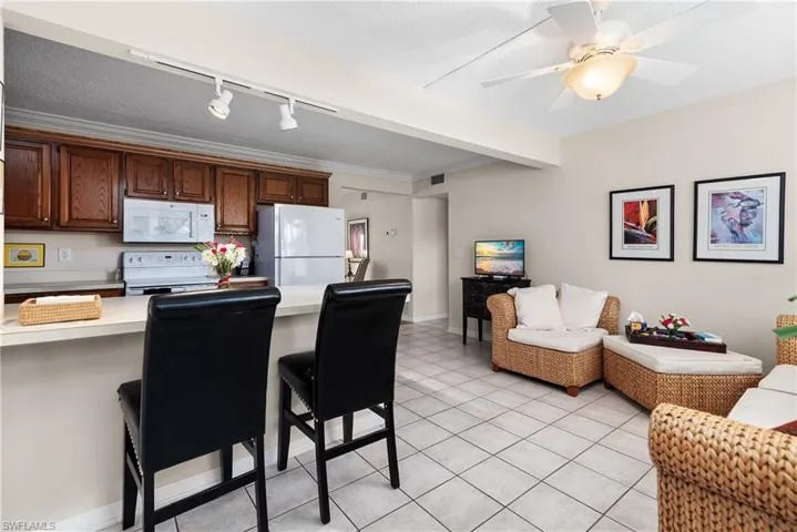 Kitchen with light countertops, a kitchen bar, open floor plan, white appliances, and a peninsula