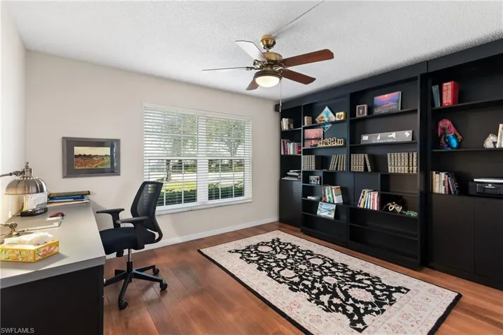 Office space with a ceiling fan, dark wood-style flooring, and a textured ceiling