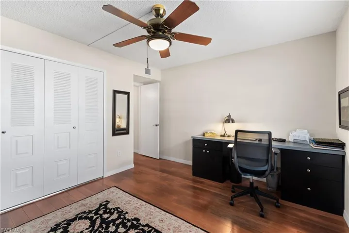 Home office featuring dark wood-style flooring, a ceiling fan, and a textured ceiling