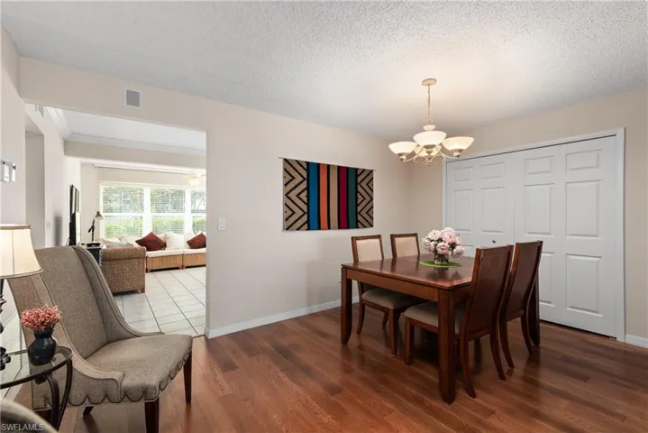 Dining room with a textured ceiling, hanging lights, and dark wood finished floors