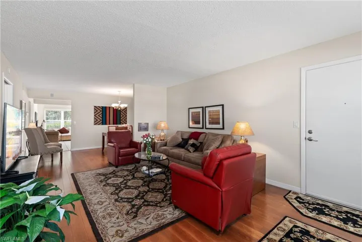 Living area with a chandelier, wood-type flooring, and a textured ceiling