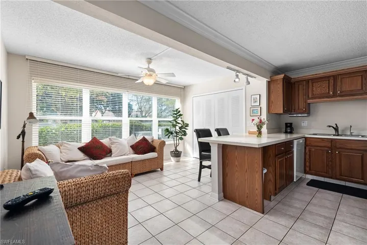 Kitchen with a textured ceiling, a breakfast bar area, light countertops, a peninsula, and light tile patterned flooring