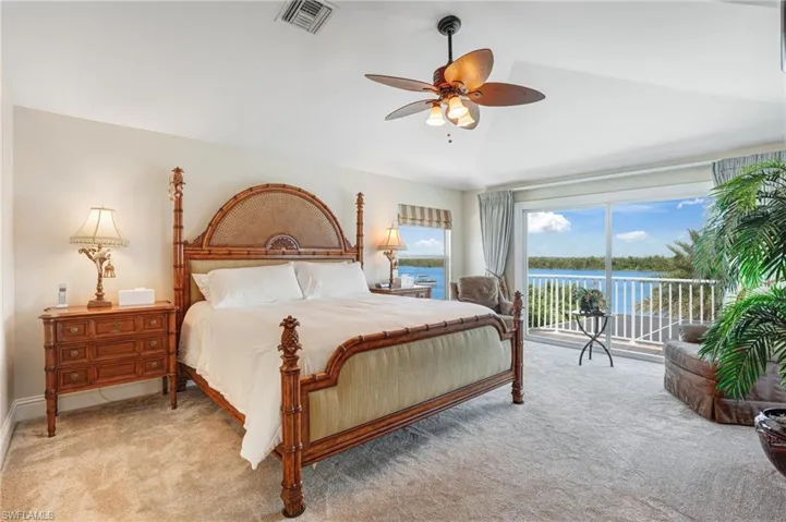 Carpeted bedroom featuring access to exterior, a water view, a ceiling fan, and vaulted ceiling - Virtually Edited Image