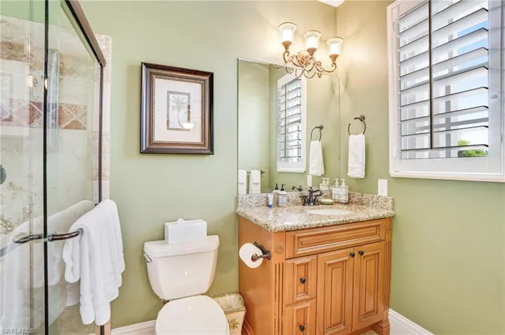 Bathroom featuring vanity, a shower stall, and suspended lighting - Virtually Edited Image